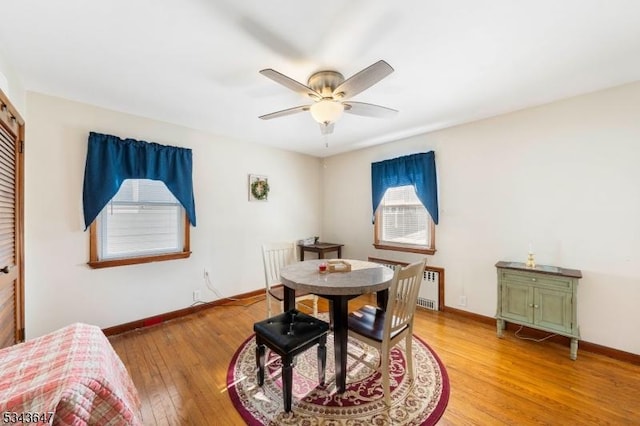 dining room featuring baseboards, light wood-style floors, ceiling fan, and radiator heating unit