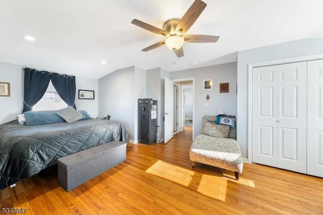 bedroom featuring a closet, ceiling fan, light wood-style floors, and vaulted ceiling