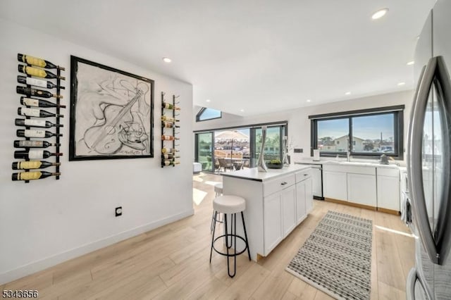 kitchen featuring white cabinetry, appliances with stainless steel finishes, a kitchen island, and light wood-style floors