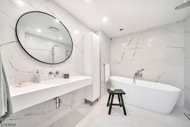 full bath featuring a soaking tub, stone wall, recessed lighting, and a sink