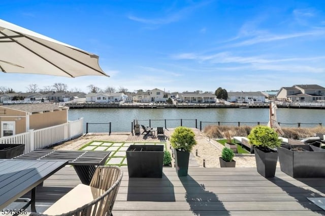 wooden terrace with a residential view, fence, and a water view