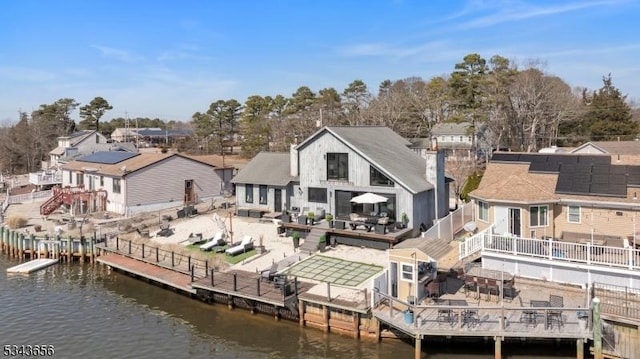 back of property with a patio, fence, and a water view