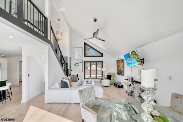 living area with stairway, baseboards, wood finished floors, and a towering ceiling