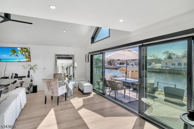 living room with lofted ceiling, light wood-style flooring, recessed lighting, and a water view