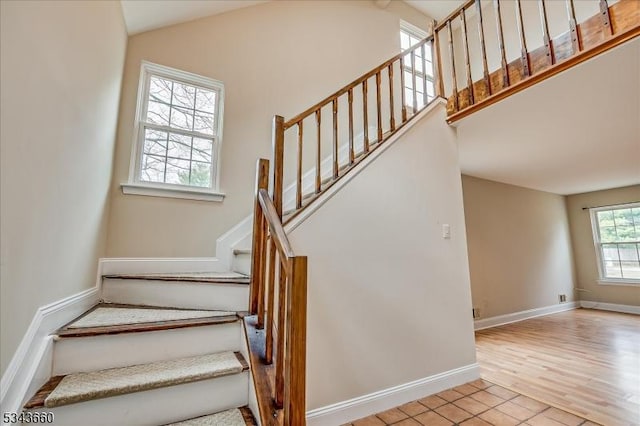 stairs with baseboards, wood finished floors, and vaulted ceiling