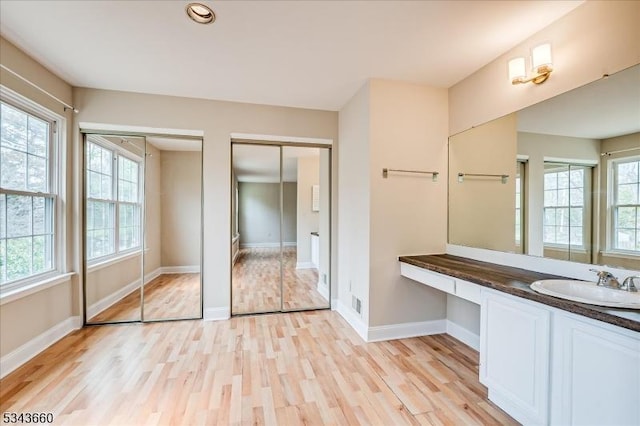 bathroom featuring baseboards, wood finished floors, and vanity