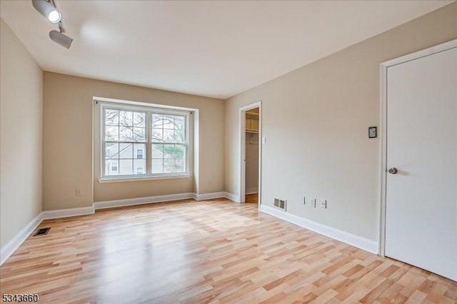 spare room with visible vents, baseboards, and light wood finished floors