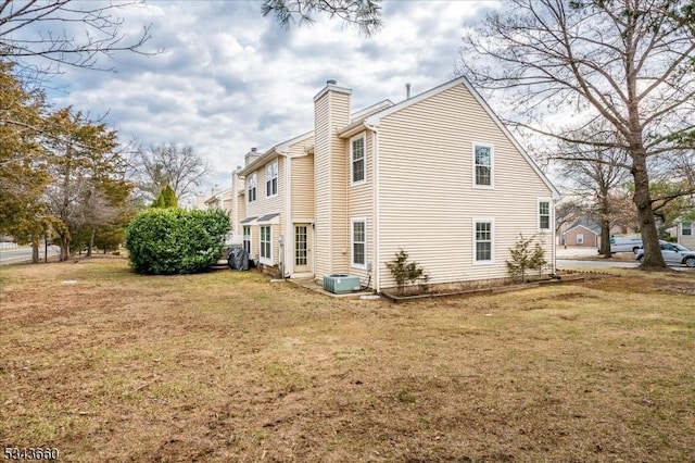 view of side of home featuring a yard, central air condition unit, and a chimney