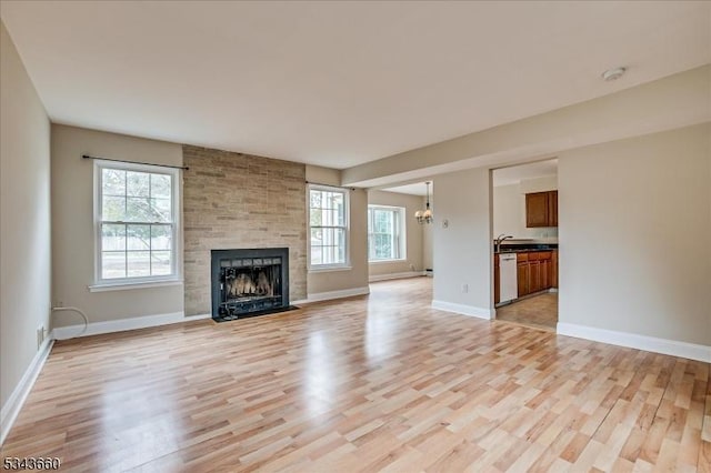 unfurnished living room with a healthy amount of sunlight, baseboards, and light wood-style floors