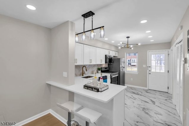 kitchen featuring a sink, tasteful backsplash, appliances with stainless steel finishes, white cabinets, and light countertops