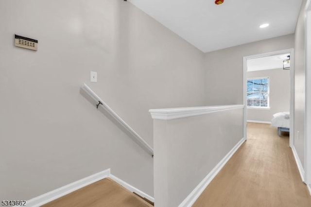 corridor with an upstairs landing, recessed lighting, light wood finished floors, and baseboards