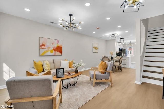 living area with recessed lighting, an inviting chandelier, light wood-style flooring, and stairs