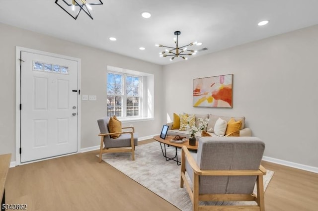 living area with recessed lighting, baseboards, an inviting chandelier, and light wood-style flooring