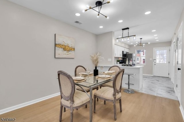 dining area featuring baseboards, a notable chandelier, and light wood-style flooring