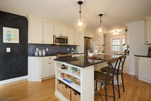 kitchen featuring open shelves, a breakfast bar area, light wood-style floors, and appliances with stainless steel finishes