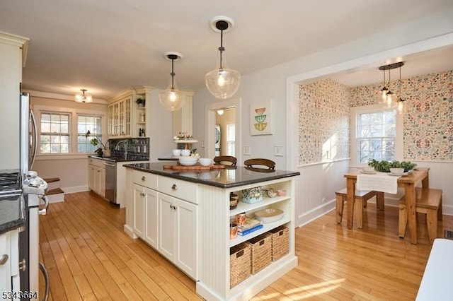 kitchen with open shelves, dishwasher, light wood-style flooring, and wainscoting