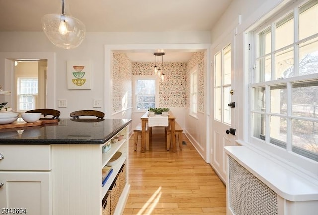 kitchen with pendant lighting, radiator heating unit, light wood-style floors, white cabinets, and wallpapered walls