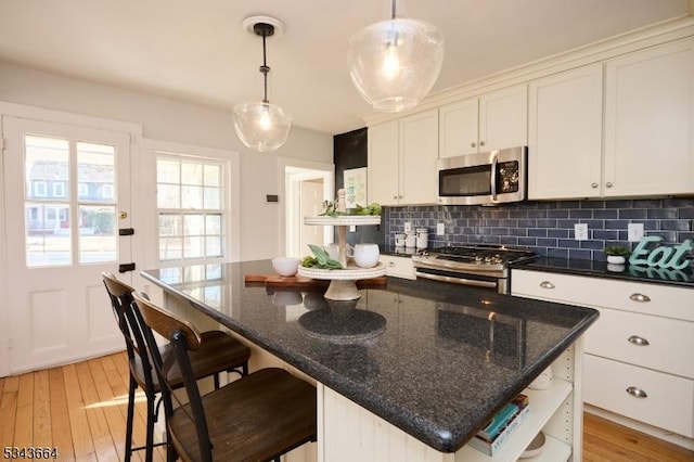 kitchen with open shelves, stainless steel appliances, light wood-style floors, and tasteful backsplash