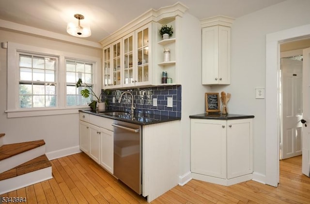 kitchen featuring a sink, backsplash, light wood-type flooring, and stainless steel dishwasher