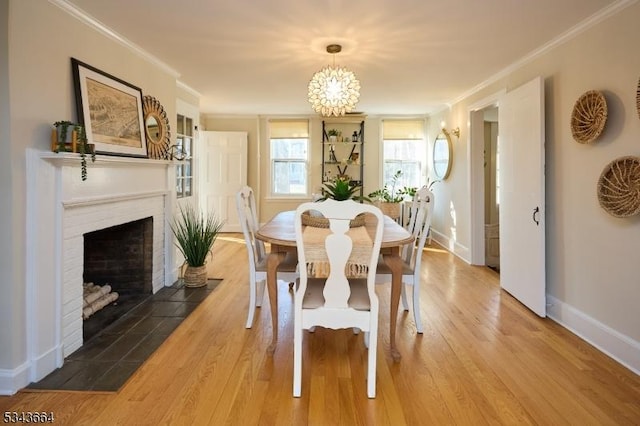 dining space with baseboards, a fireplace, wood finished floors, and crown molding