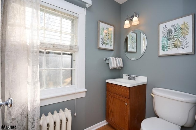 bathroom with radiator, toilet, vanity, and baseboards