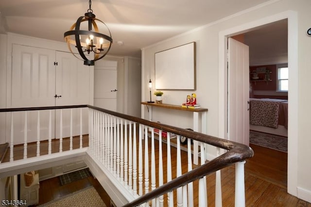 hallway featuring ornamental molding, wood finished floors, and a chandelier