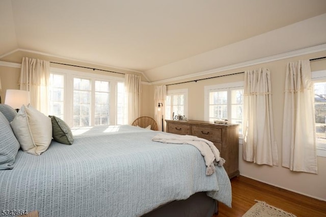 bedroom featuring ornamental molding, lofted ceiling, and wood finished floors