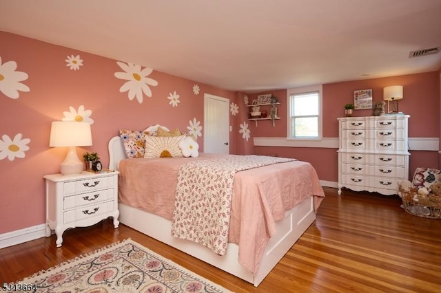 bedroom featuring wood finished floors, visible vents, a closet, and baseboards