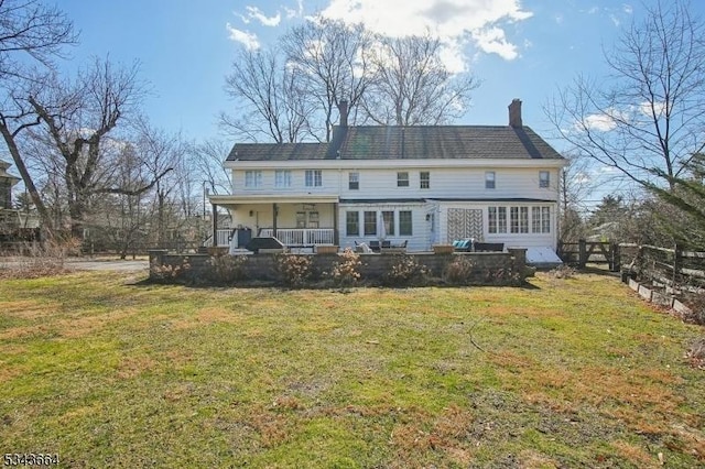 rear view of property featuring a yard, fence, covered porch, and a chimney