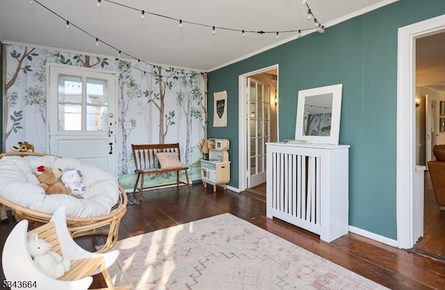 sitting room featuring wood finished floors, baseboards, and ornamental molding