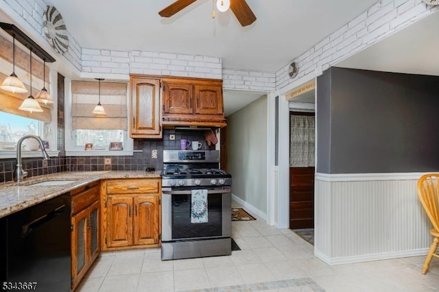 kitchen featuring brick wall, a sink, ceiling fan, black dishwasher, and stainless steel gas range oven