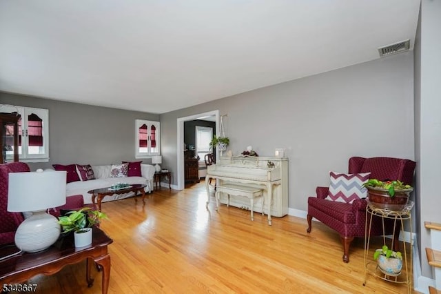 living area with visible vents, light wood-type flooring, and baseboards