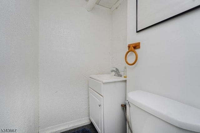 bathroom featuring baseboards, toilet, and vanity