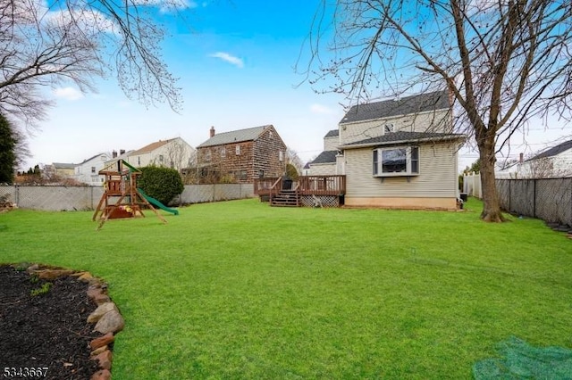 view of yard featuring a deck, a playground, and a fenced backyard