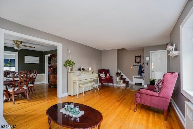 living area featuring stairway, light wood-style flooring, radiator heating unit, and baseboards