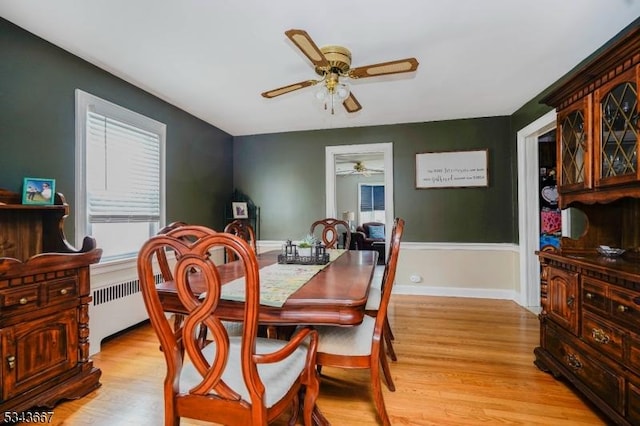 dining space featuring light wood-type flooring, baseboards, radiator, and ceiling fan