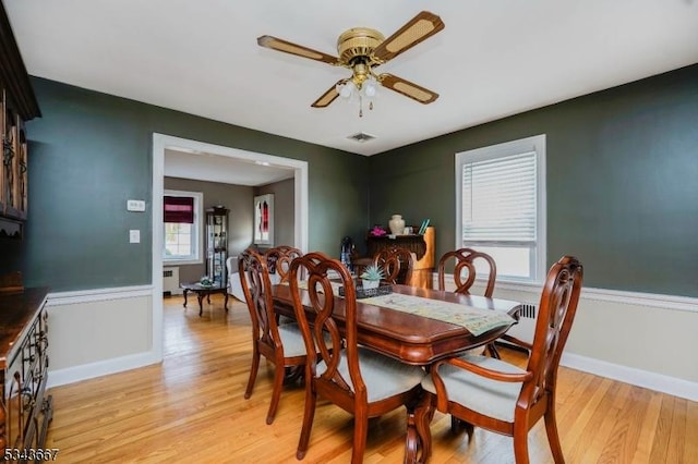 dining area featuring visible vents, radiator, baseboards, light wood-type flooring, and a ceiling fan