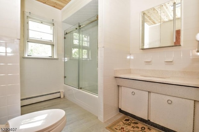 full bathroom with combined bath / shower with glass door, a baseboard heating unit, tile walls, and vanity