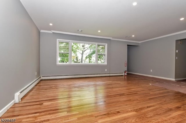 spare room featuring a baseboard heating unit, crown molding, and light wood finished floors