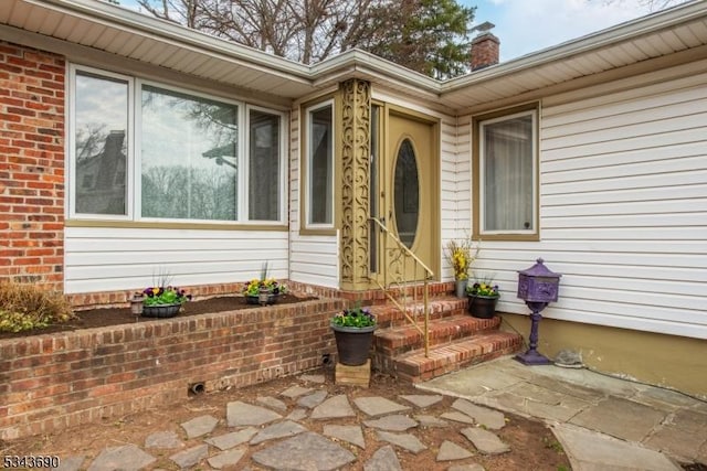 view of exterior entry featuring brick siding and a chimney