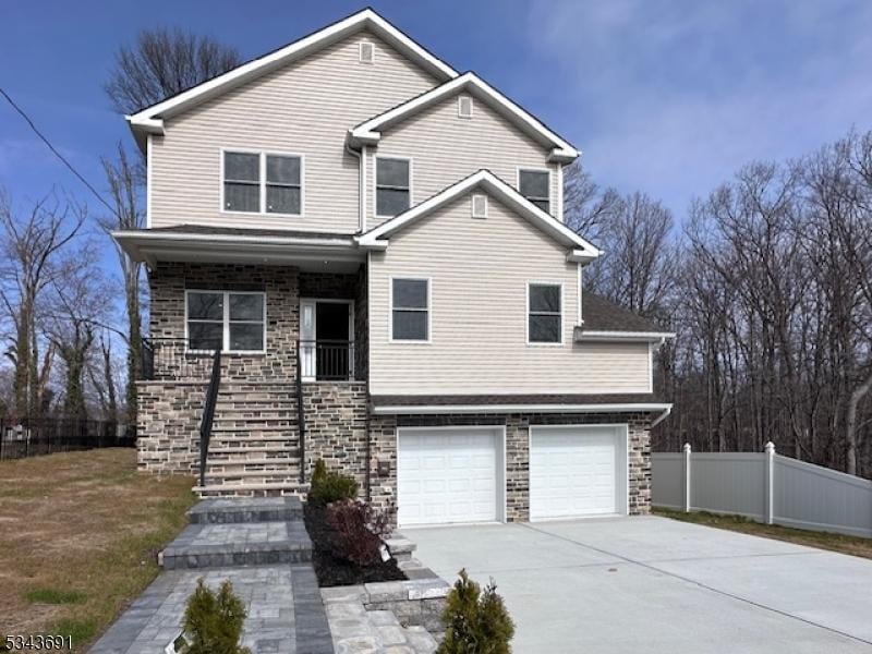 view of front of property featuring stone siding, fence, stairway, concrete driveway, and an attached garage