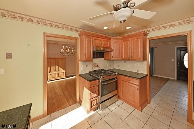 kitchen featuring dark countertops, tasteful backsplash, stainless steel range with gas cooktop, under cabinet range hood, and light tile patterned flooring