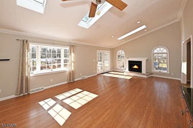 unfurnished living room with wood finished floors, visible vents, a warm lit fireplace, and ornamental molding