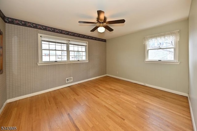 empty room featuring plenty of natural light, baseboards, and wood finished floors