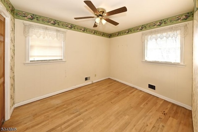 spare room with light wood-type flooring, baseboards, visible vents, and ceiling fan