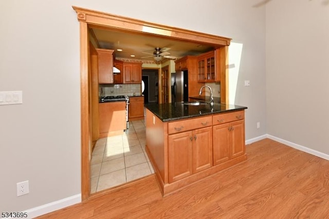 kitchen featuring decorative backsplash, a sink, range with gas cooktop, stainless steel fridge, and glass insert cabinets