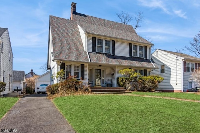 view of front of home with a front yard, a porch, a chimney, and a shingled roof