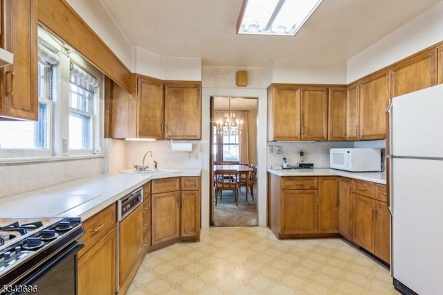 kitchen with white appliances, a healthy amount of sunlight, light floors, a sink, and brown cabinets