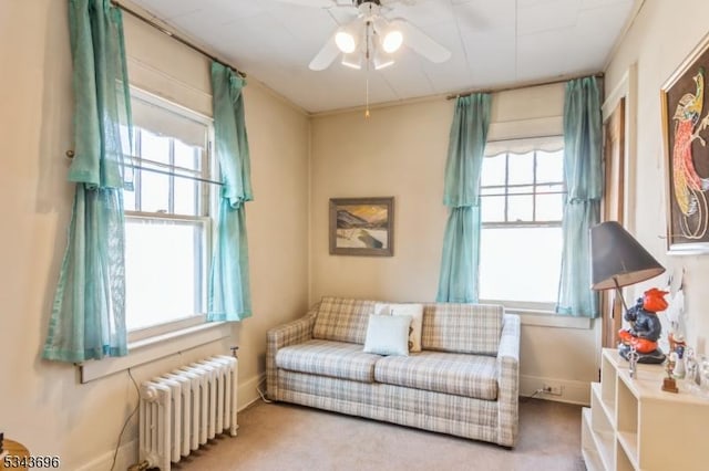 living area with a healthy amount of sunlight, baseboards, radiator heating unit, and ceiling fan