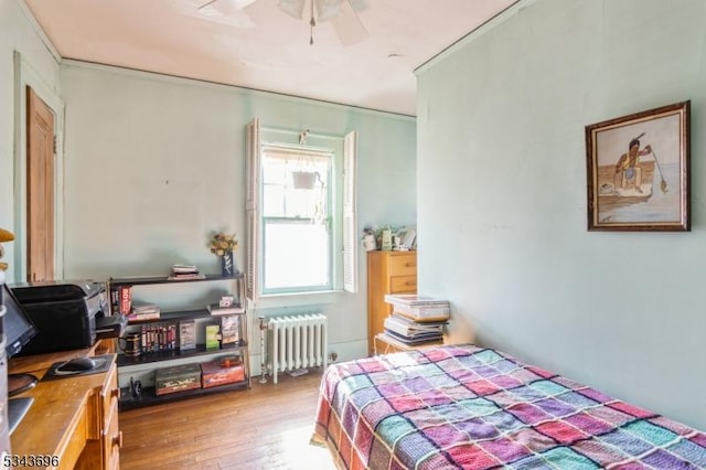 bedroom featuring radiator, crown molding, and wood finished floors